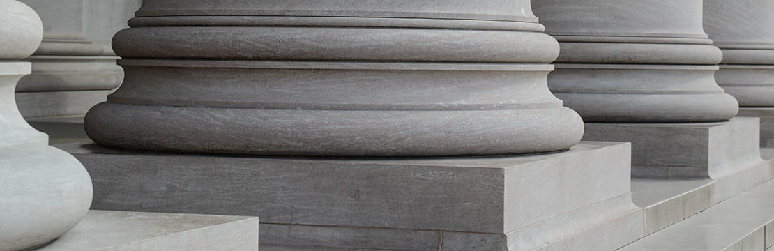 ) Close-up of government building columns, symbolizing the U.S. political landscape and the potential impact of midterm election outcomes on financial markets and economic policy.